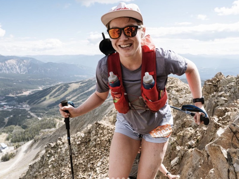 Fem grinning on the rocky ridgeline above Big Sky, poles in hand.