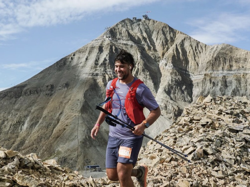 Zach running a scree traverse with Lone Peak behind him.